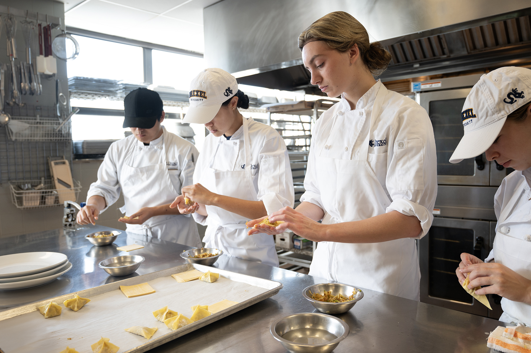 four students in kitchen making potstickers